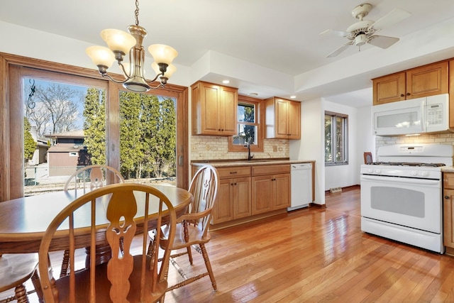 kitchen featuring white appliances, light countertops, light wood-style flooring, and backsplash