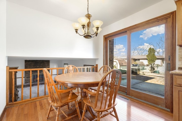 dining space featuring visible vents, light wood-style flooring, and a notable chandelier