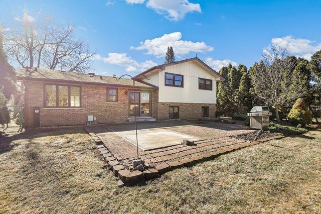 rear view of property featuring brick siding, a lawn, and a patio area