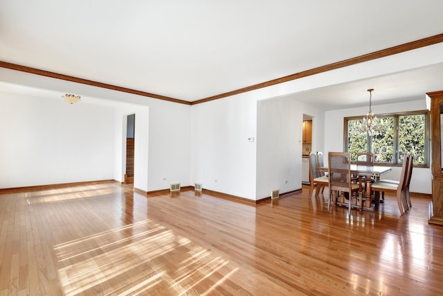 living area with visible vents, baseboards, crown molding, light wood-style floors, and a notable chandelier