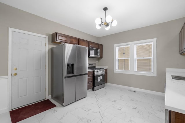 kitchen with stainless steel appliances, baseboards, marble finish floor, decorative light fixtures, and an inviting chandelier