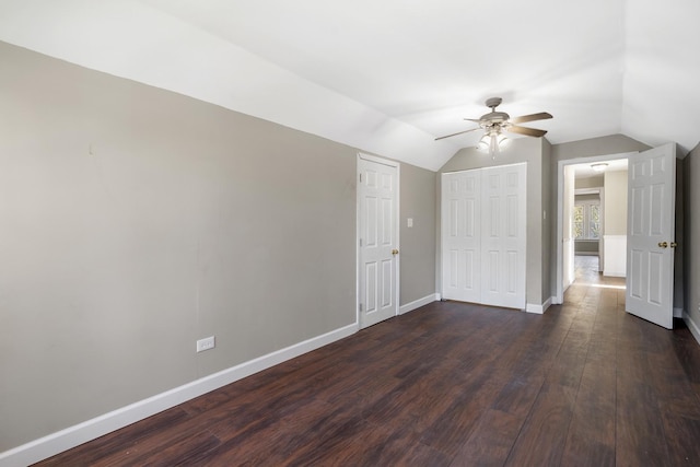 unfurnished bedroom with dark wood finished floors, a closet, a ceiling fan, vaulted ceiling, and baseboards