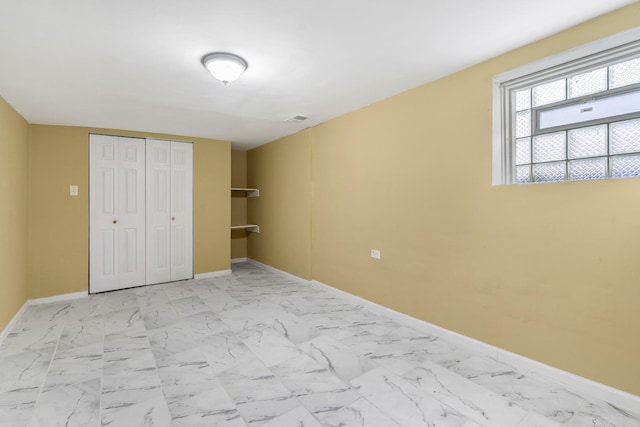 unfurnished bedroom featuring marble finish floor, a closet, visible vents, and baseboards