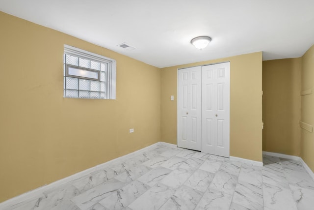 unfurnished bedroom with marble finish floor, baseboards, visible vents, and a closet