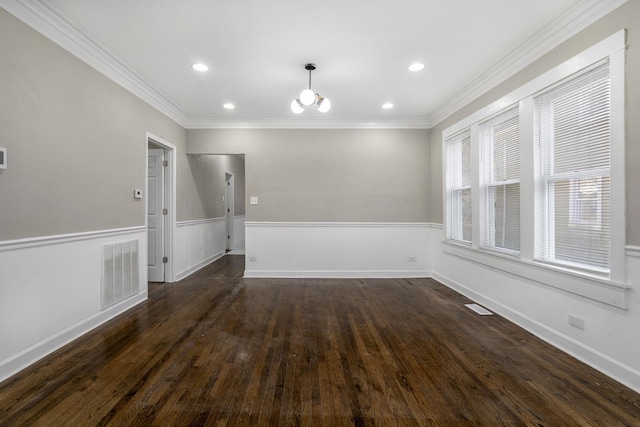 spare room with dark wood-style floors, a wainscoted wall, visible vents, and crown molding