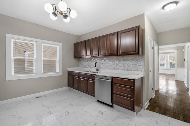 kitchen with marble finish floor, light countertops, dark brown cabinetry, a sink, and dishwasher