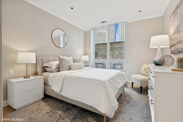 bedroom featuring floor to ceiling windows, visible vents, wood finished floors, and ornamental molding