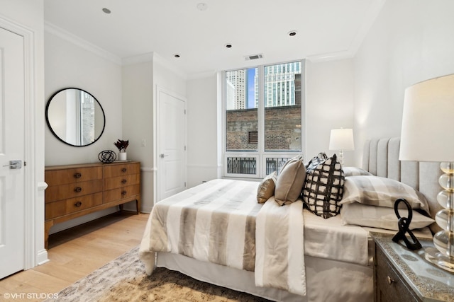 bedroom featuring light wood-style flooring, floor to ceiling windows, visible vents, and crown molding