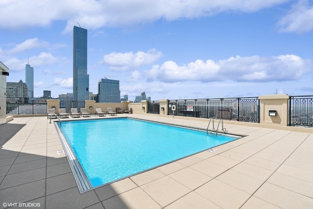 pool featuring a view of city, a patio, and fence