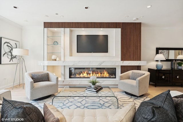 living area featuring light wood finished floors, recessed lighting, ornamental molding, a high end fireplace, and baseboards