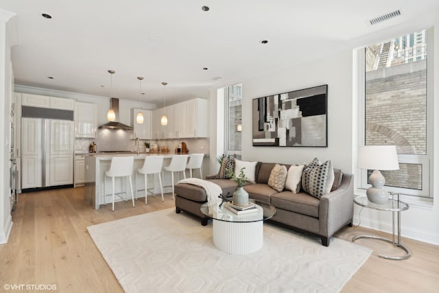 living room with baseboards, visible vents, and light wood-style floors