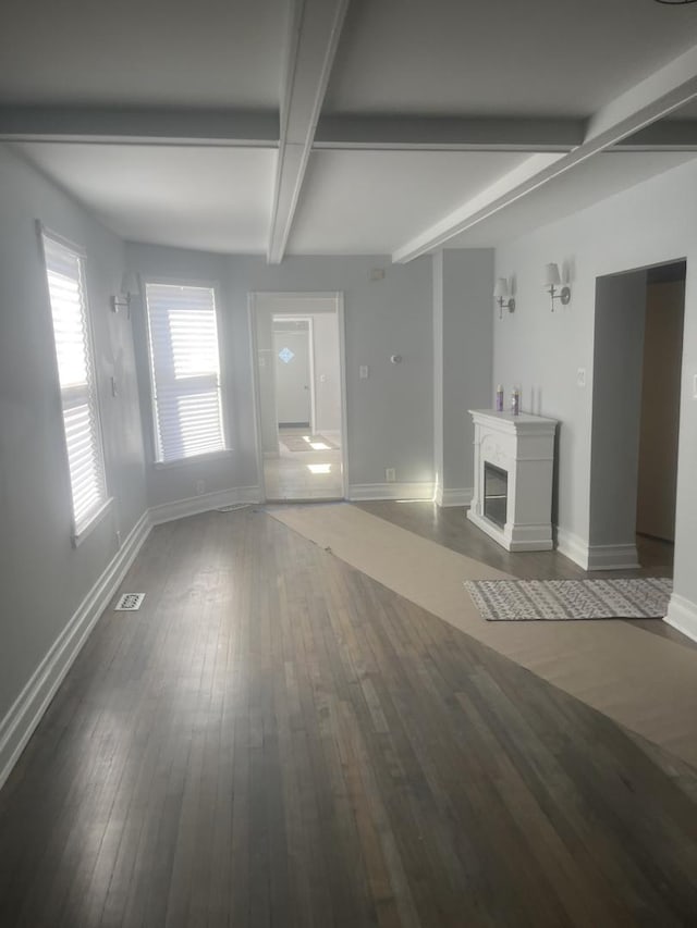 unfurnished living room with a fireplace, baseboards, dark wood finished floors, and beam ceiling