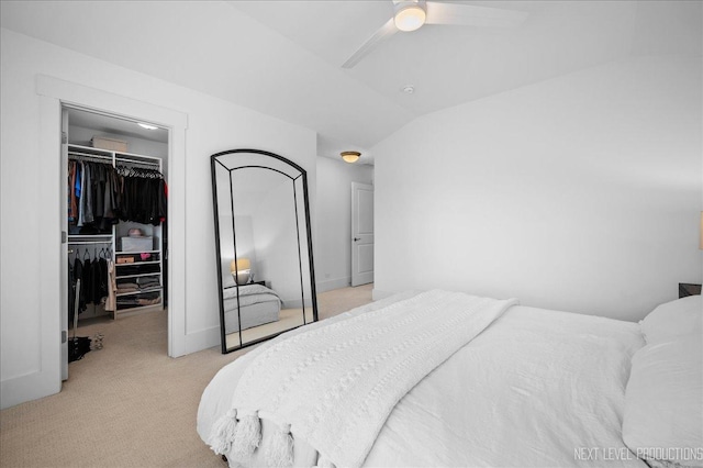 bedroom featuring ceiling fan, light carpet, vaulted ceiling, a closet, and a walk in closet