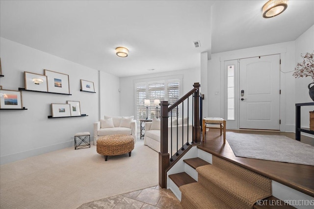 entryway featuring light carpet, visible vents, stairs, and baseboards