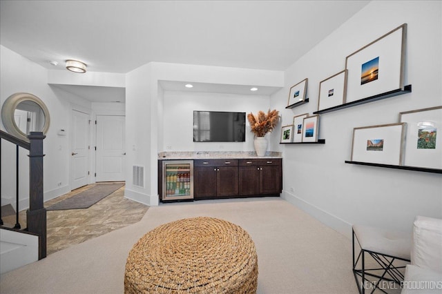 bar featuring light carpet, beverage cooler, visible vents, baseboards, and stairway