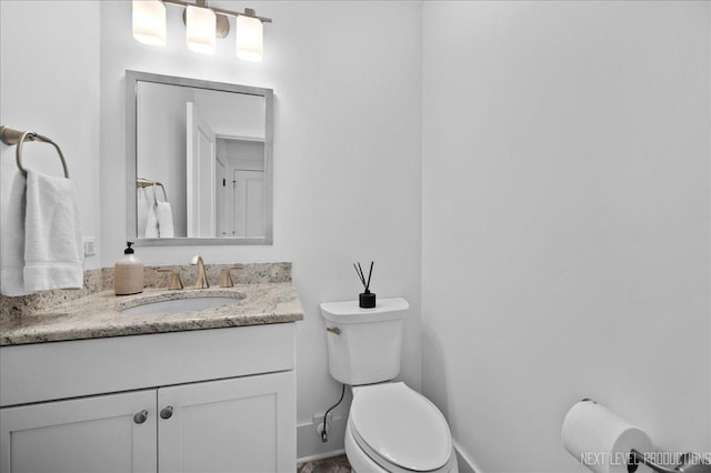 half bathroom with vanity, toilet, and baseboards