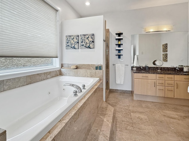 bathroom with tiled shower, a tub with jets, and double vanity