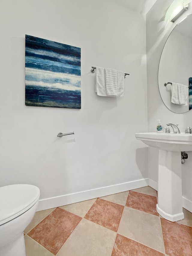 half bath with tile patterned flooring, toilet, and baseboards