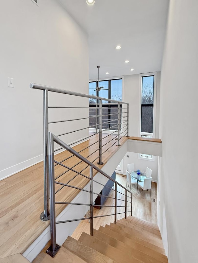 staircase with baseboards, wood finished floors, and recessed lighting