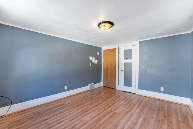 empty room featuring light wood-type flooring, visible vents, and baseboards