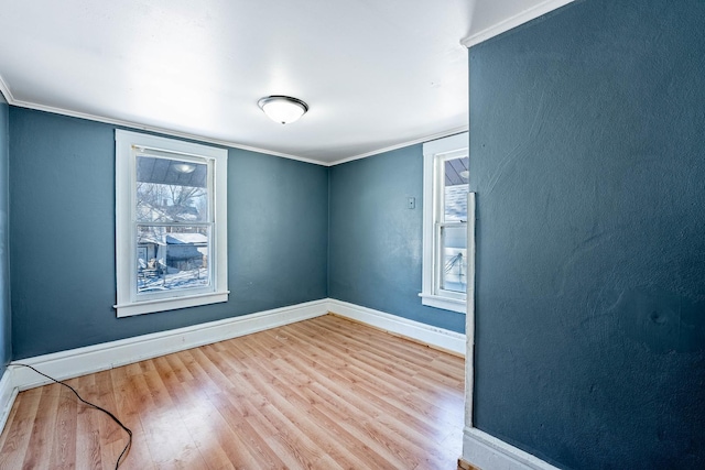 empty room featuring light wood-style floors, baseboards, and crown molding