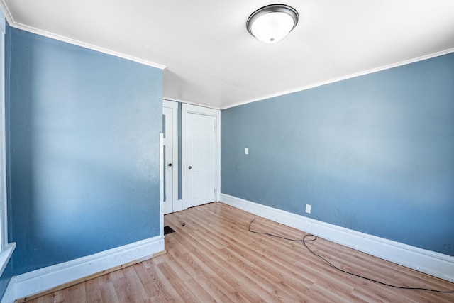 spare room with ornamental molding, light wood-type flooring, and baseboards