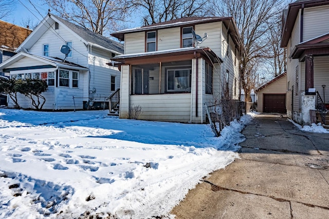 american foursquare style home featuring a sunroom, a detached garage, and an outbuilding