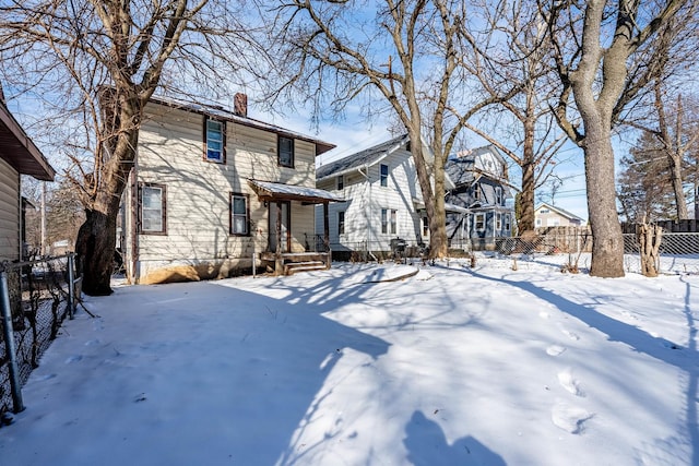 snow covered property featuring a chimney, fence, and a residential view