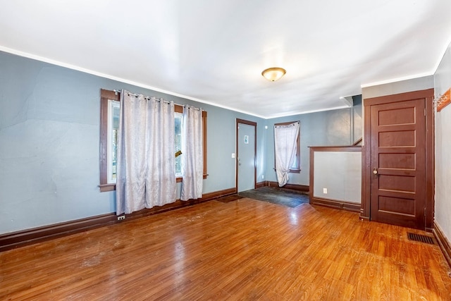 foyer entrance with ornamental molding, visible vents, baseboards, and wood finished floors