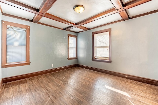 spare room featuring coffered ceiling, wood finished floors, visible vents, baseboards, and beamed ceiling