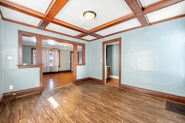 empty room with beam ceiling, visible vents, wood finished floors, coffered ceiling, and baseboards