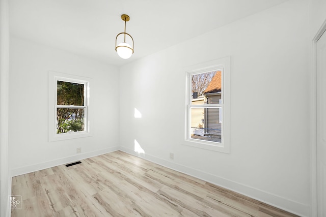 spare room featuring baseboards, visible vents, and light wood-style flooring