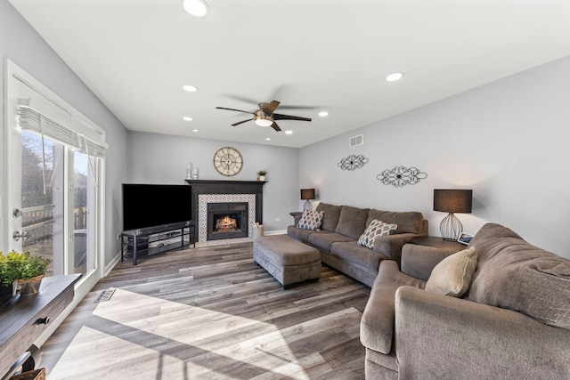 living room featuring recessed lighting, a ceiling fan, wood finished floors, and a tiled fireplace