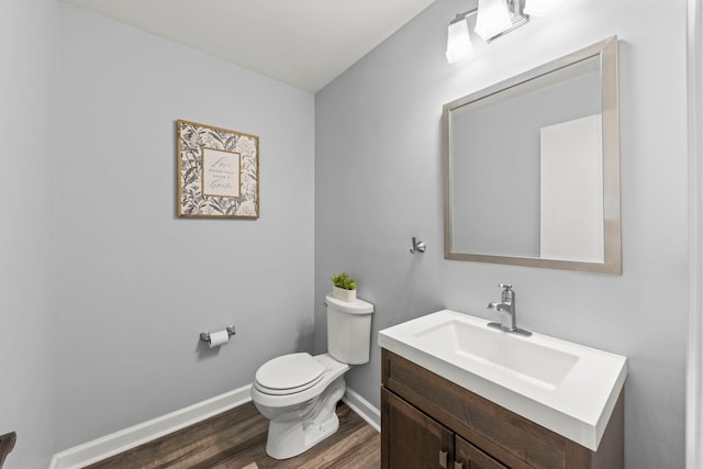 half bath featuring baseboards, toilet, wood finished floors, and vanity