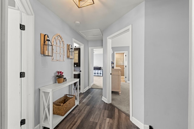 hall featuring dark wood finished floors, visible vents, attic access, and baseboards