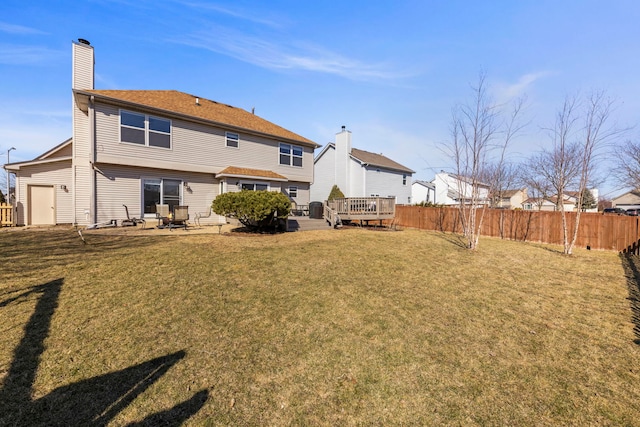 rear view of house with a wooden deck, a lawn, a chimney, and fence