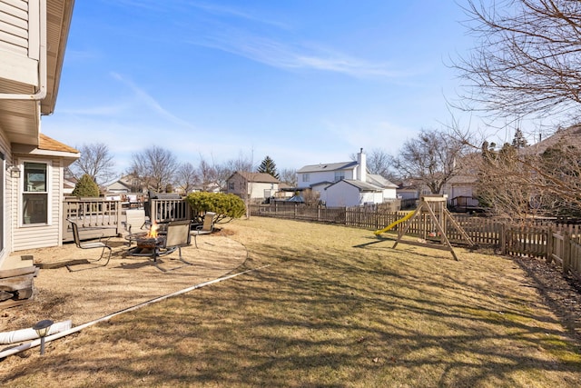 view of yard with a playground, a fenced backyard, a residential view, and a fire pit