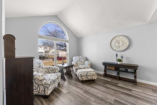 living area featuring vaulted ceiling, wood finished floors, and baseboards