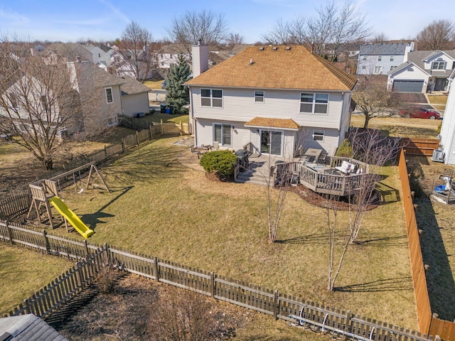 back of house with a deck, a chimney, a playground, and a yard