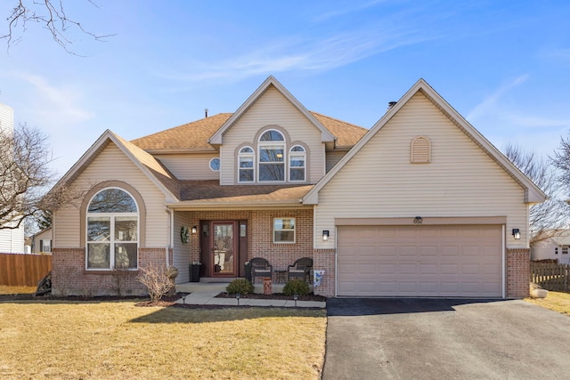 traditional-style house featuring aphalt driveway, brick siding, a front yard, and fence