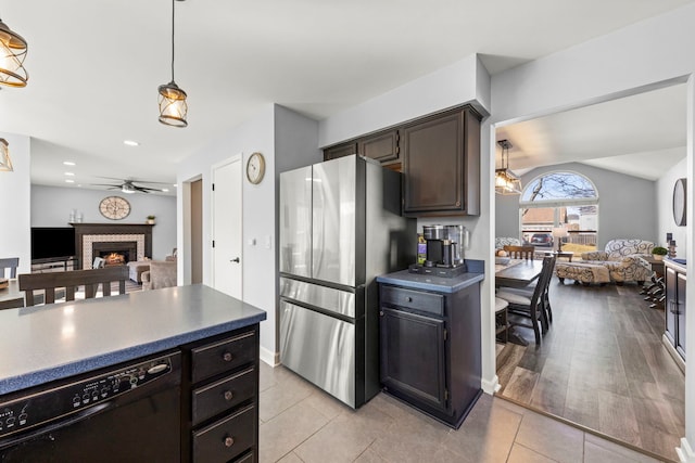 kitchen featuring a fireplace, freestanding refrigerator, dark brown cabinetry, black dishwasher, and open floor plan