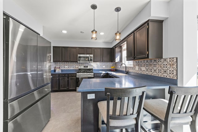 kitchen featuring stainless steel appliances, dark countertops, dark brown cabinets, and a peninsula