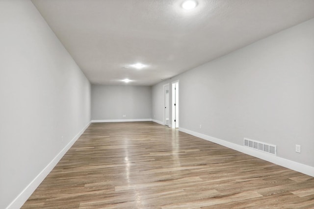 unfurnished room with light wood-type flooring, visible vents, and baseboards