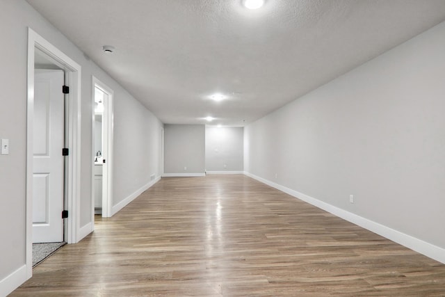 unfurnished room featuring baseboards, a textured ceiling, and light wood finished floors