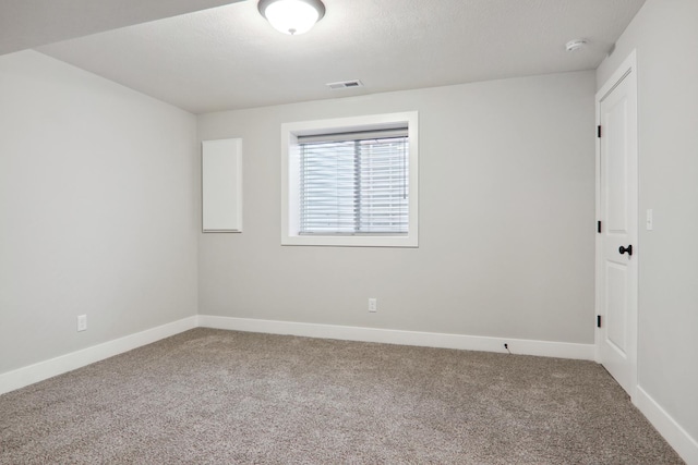 carpeted empty room with visible vents, a textured ceiling, and baseboards