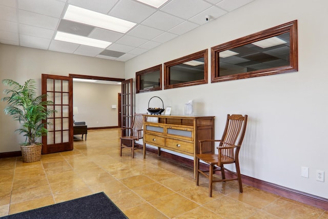 interior space with a paneled ceiling, french doors, and baseboards