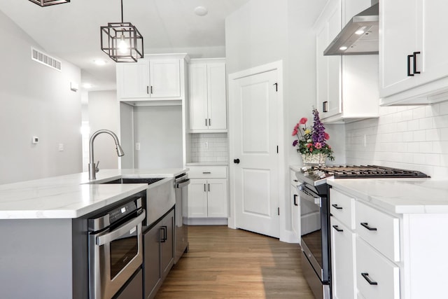 kitchen featuring visible vents, white cabinets, hanging light fixtures, appliances with stainless steel finishes, and wall chimney exhaust hood