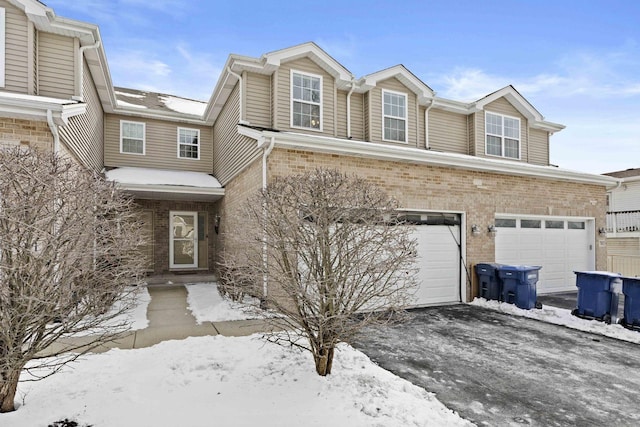 view of property featuring a garage, driveway, and brick siding