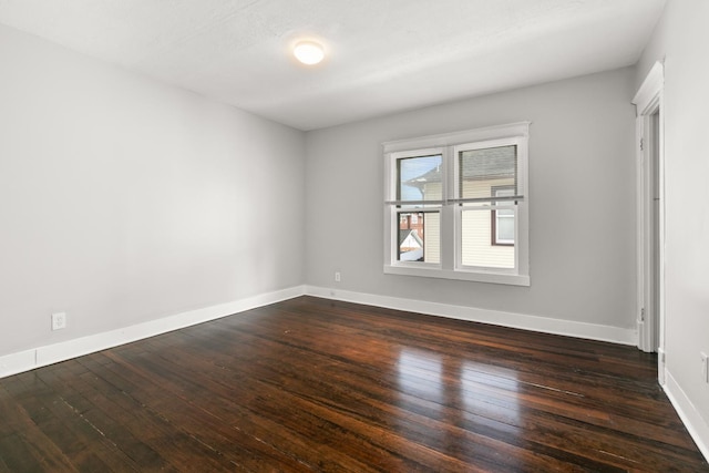 empty room with baseboards and dark wood finished floors