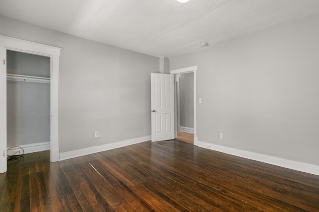 unfurnished bedroom with dark wood-style floors, a closet, and baseboards